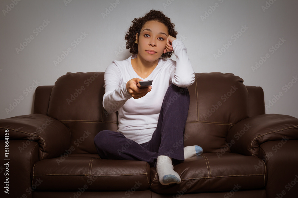 Serious woman holding remote control and watching TV Serious woman holding remote control and watching TV