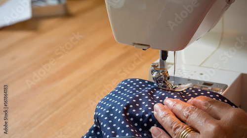 female hand using sewing machine stitching fabic in studio