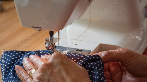 female hand using sewing machine stitching fabic in studio