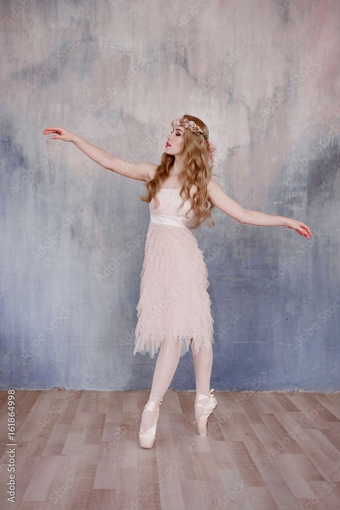 Fototapeta premium Beautiful legs of young ballerina dancing at white wooden floor background, with copy space. Ballet practice. Beautiful slim graceful ballet dancer. Spring and romantic atmosphere