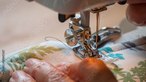 female hand using sewing machine stitching fabic in studio