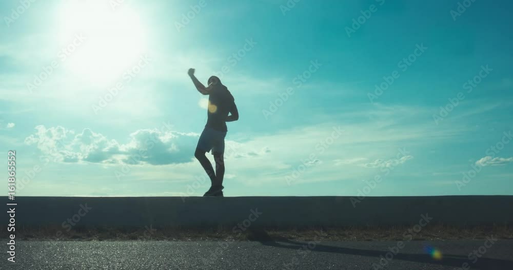 FIXED Side view of handsome African American man practicing boxing moves on seaside promenade at sunset. 4K UHD FIXED Side view of handsome African American man practicing boxing moves on seaside promenade at sunset. 4K UHD