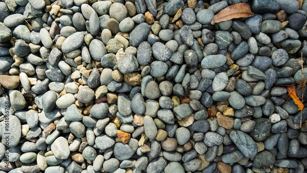 Lots of grey, black, white pebble stone texture background with dried orange leaves Lots of grey, black, white pebble stone texture background with dried orange leaves