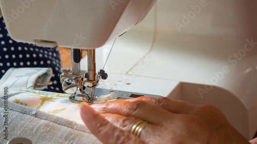 female hand using sewing machine stitching fabic in studio