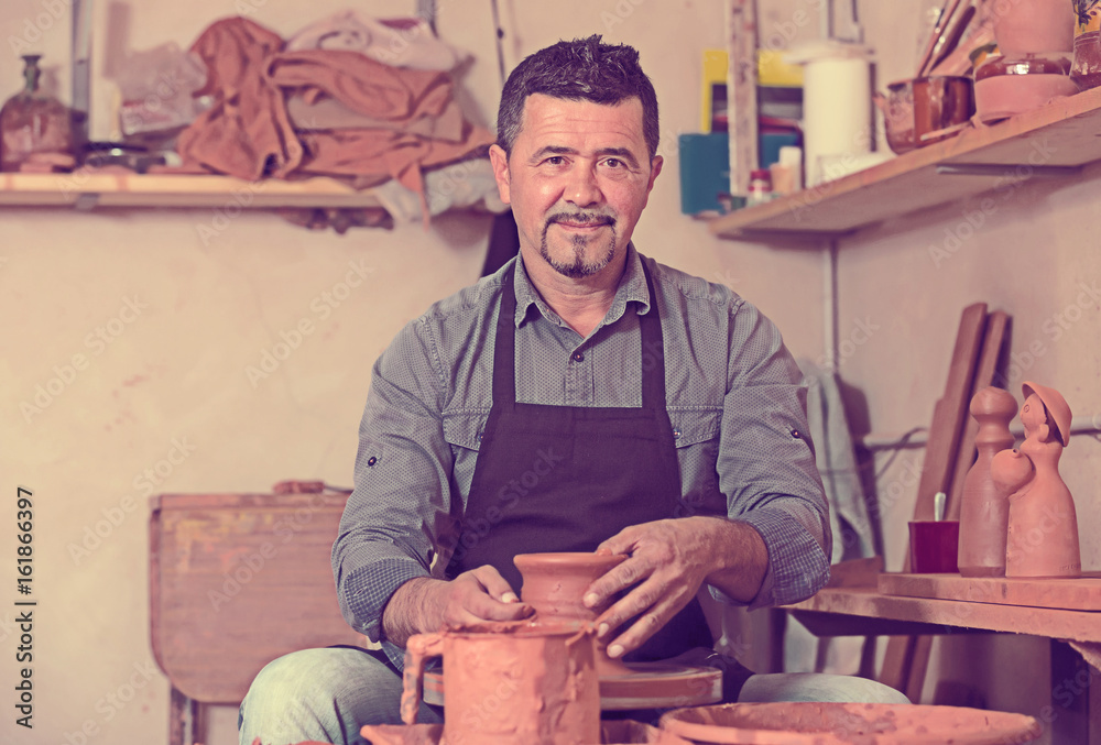 Cheerful male working with clay on pottery wheel