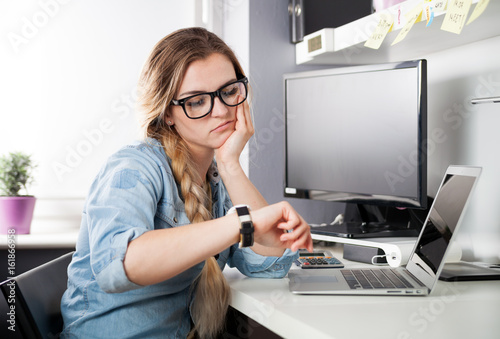 Obraz na plátne Tired woman at home office looking at watch