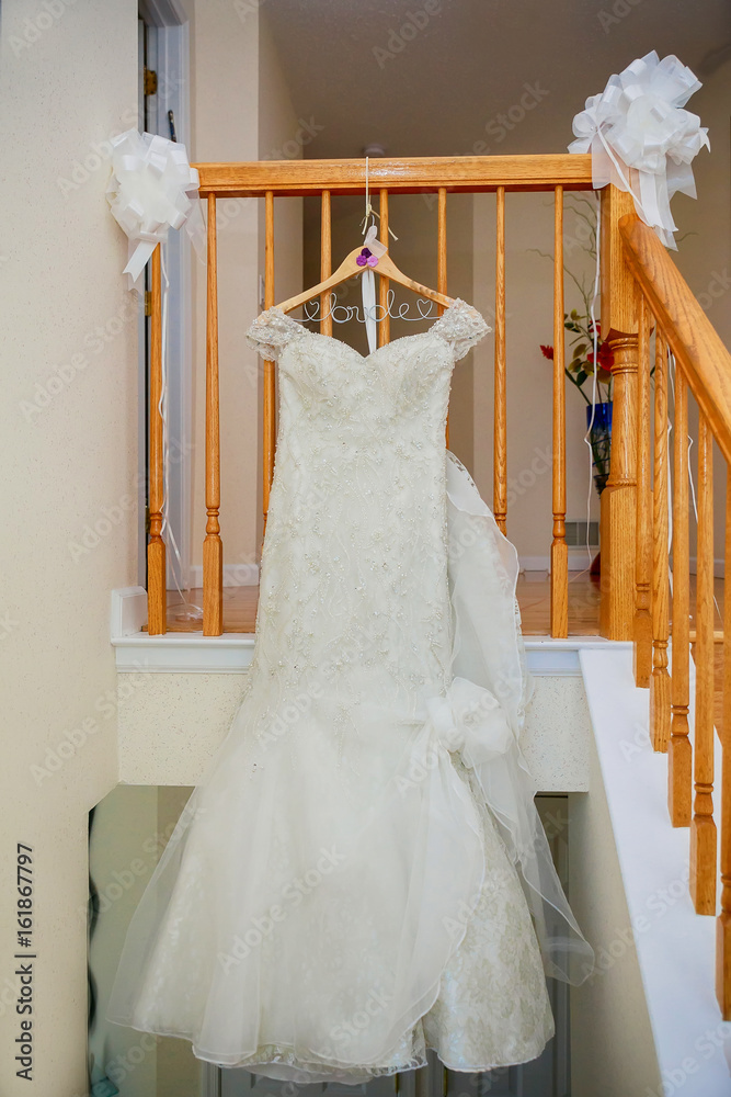 The perfect wedding dress with a full skirt on a hanger in the room The perfect wedding dress with a full skirt on a hanger in the room
