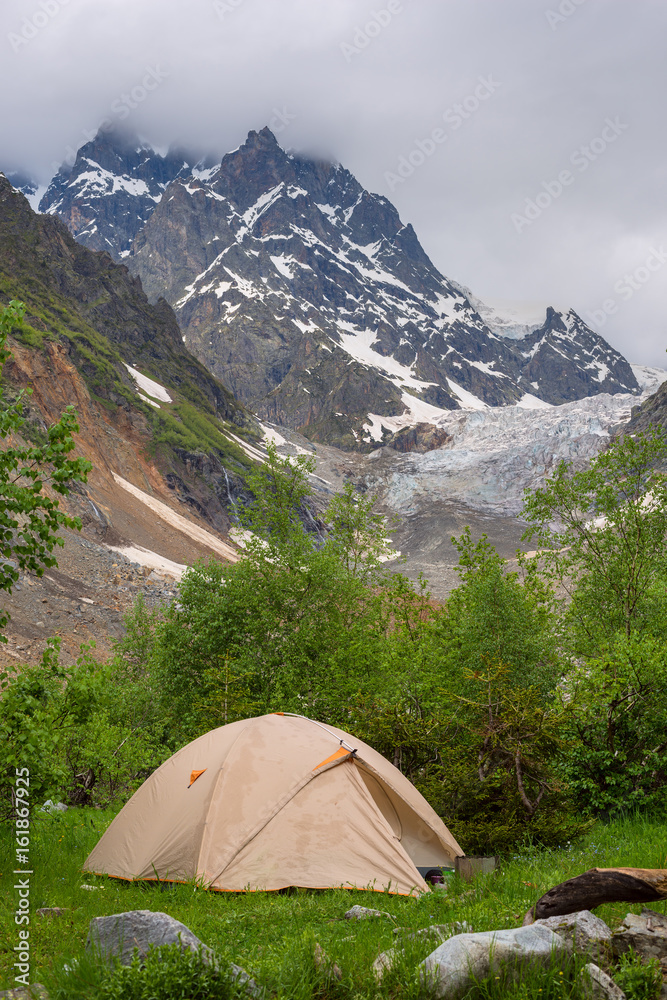Tent of travelers next to a glacier in a mountain gorge