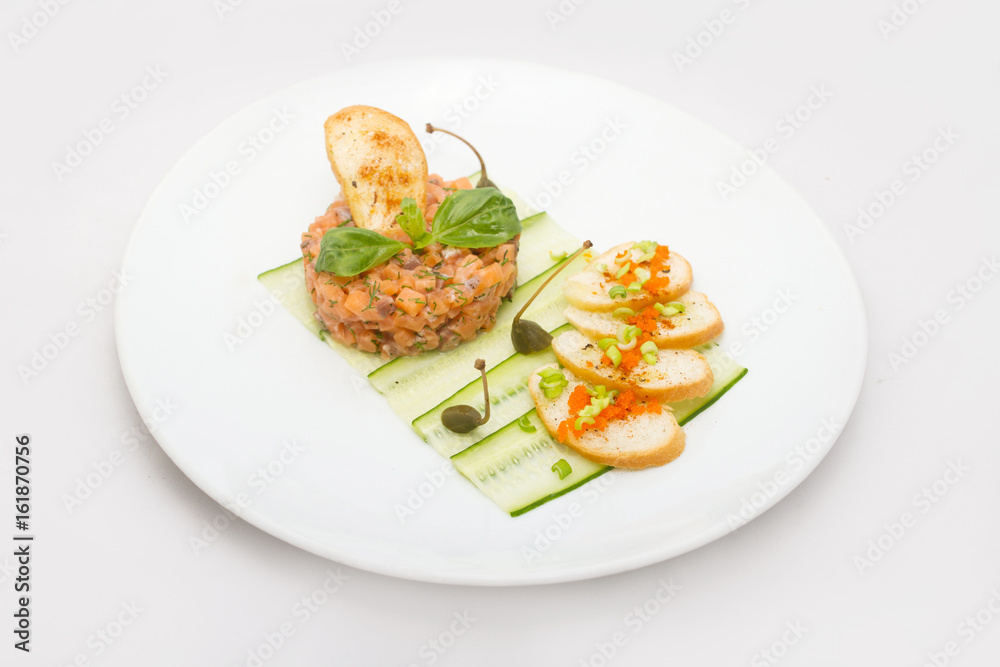 Salmon tartare on a white plate with green leaves Salmon tartare on a white plate with green leaves