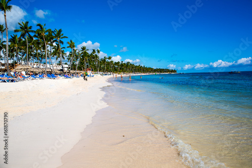 Fototapeta Naklejka Na Ścianę i Meble -  beautiful landscape with big green palm trees in the foreground to the background of tourist umbrellas and sunbeds on a beautiful exotic beach