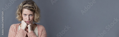 Tableau sur toile frustrated young childish woman sulking with fists under chin