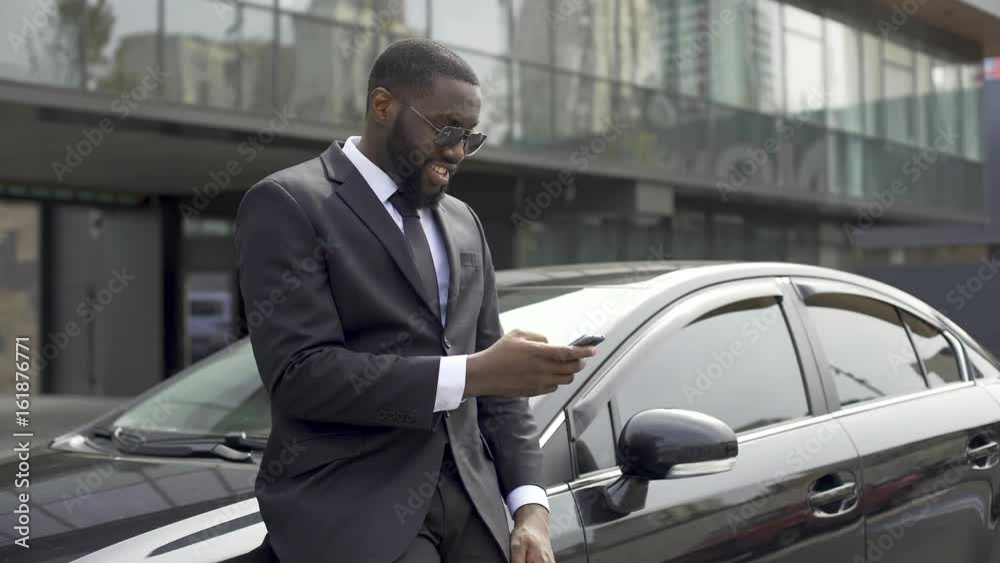 Masculine man in expensive suit waiting for companion, scrolling news on gadget Masculine man in expensive suit waiting for companion, scrolling news on gadget