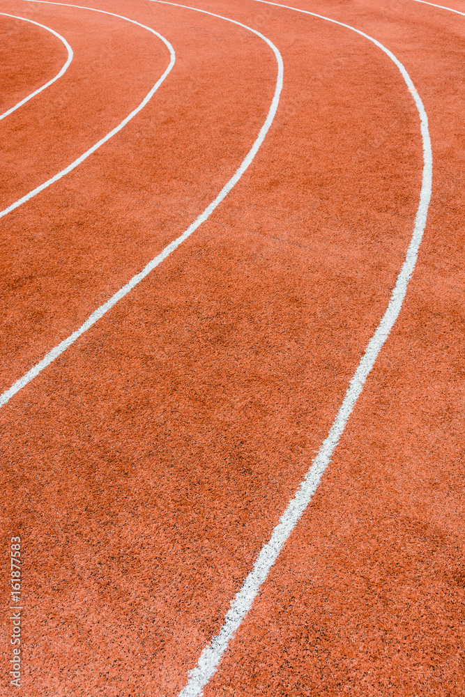 Close-up view of a red athletics track with white lines delimiting the lanes. Close-up view of a red athletics track with white lines delimiting the lanes.