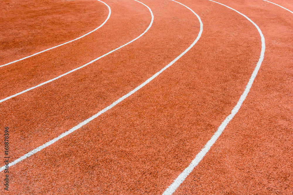 Close-up view of a red athletics track with white lines delimiting the lanes. Close-up view of a red athletics track with white lines delimiting the lanes.