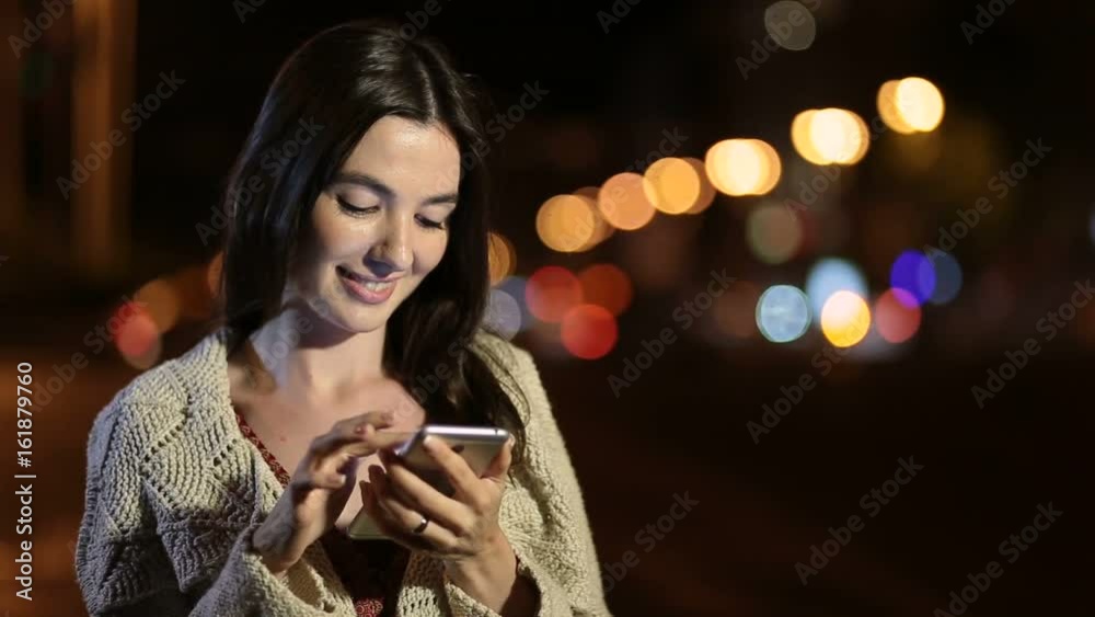 Happy girl texting message on phone in night city Happy girl texting message on phone in night city