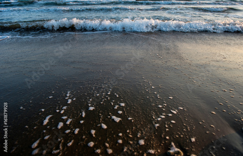 Waves approaching sandy beach during the sunset