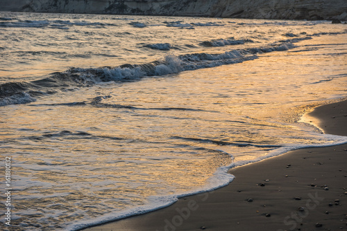 Waves approaching sandy beach during sunset
