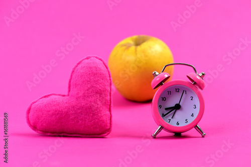 Composition of alarm clock, heart and apple