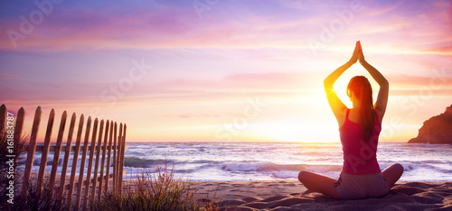 Fotografie Woman Doing Yoga Fitness In The Beach At Sunset