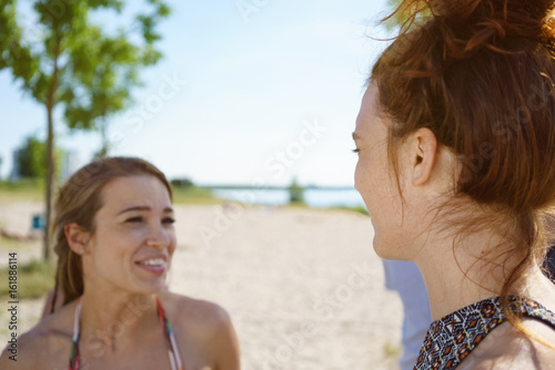 Young woman on the beach sharing a joke with her friend