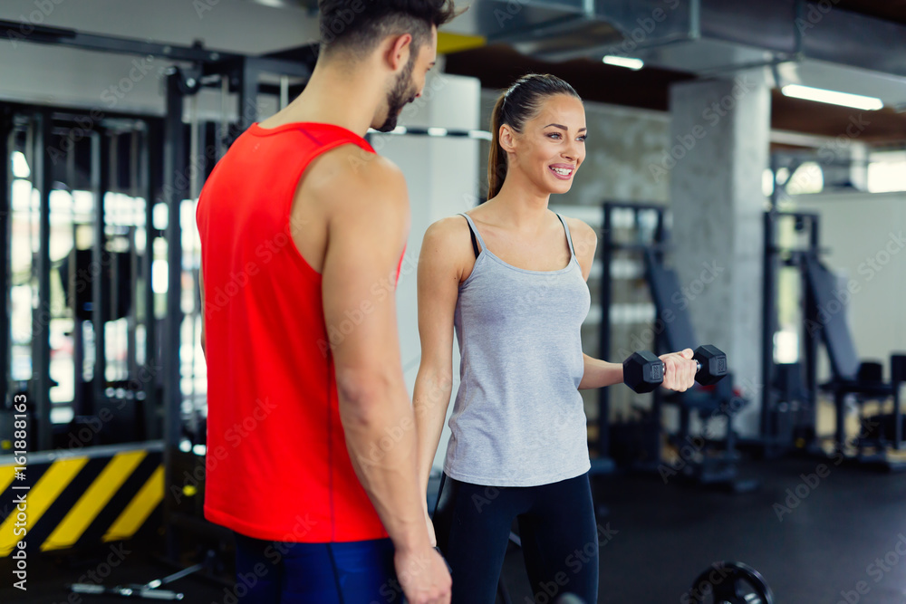 Young adult woman working out in gym with trainer