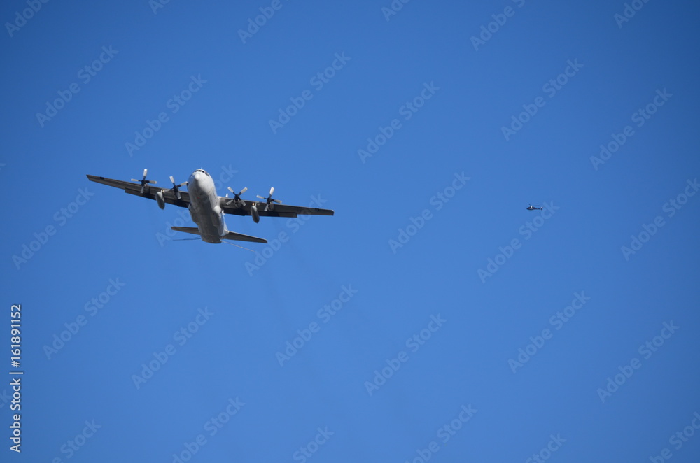 Military Four Helix Aircraft Flying with an Helicopter on the background Military Four Helix Aircraft Flying with an Helicopter on the background