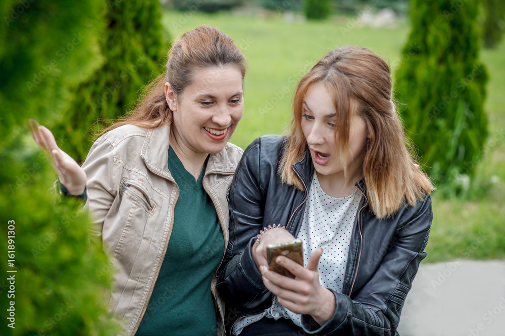 Two amazed women friends sharing social media outdoor Two amazed women friends sharing social media outdoor