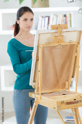 young woman with an easel paints a picture