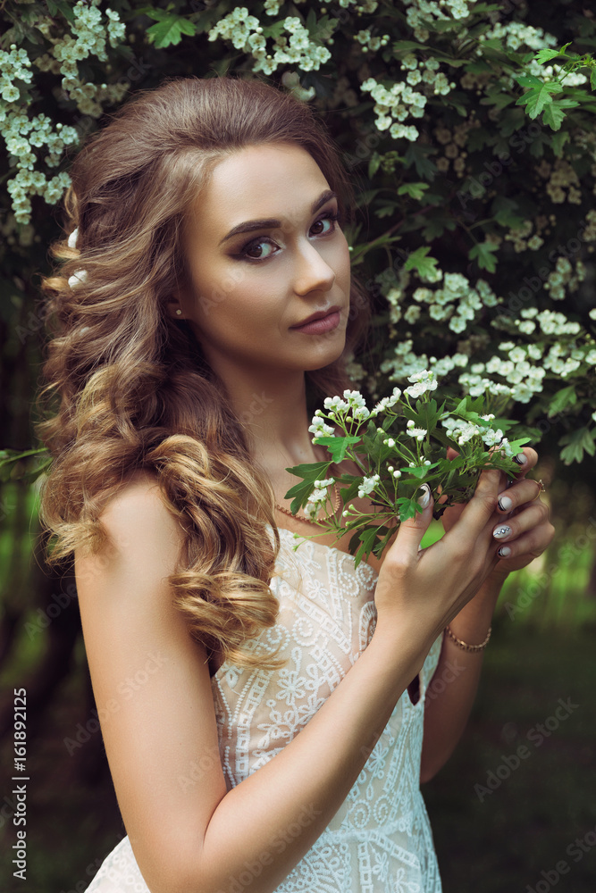Pretty woman enjoying smell flowers. Portrait of young beautiful woman posing among blooming trees Pretty woman enjoying smell flowers. Portrait of young beautiful woman posing among blooming trees