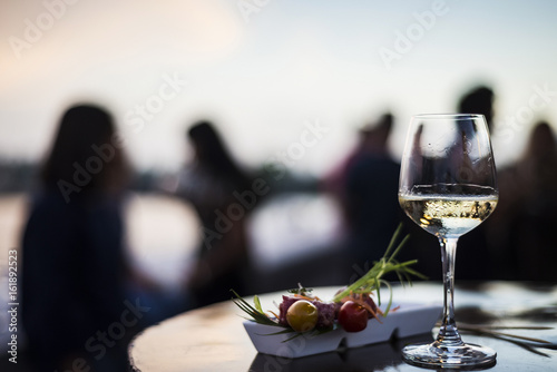 glass of white wine with gourmet food tapa snacks outside photo