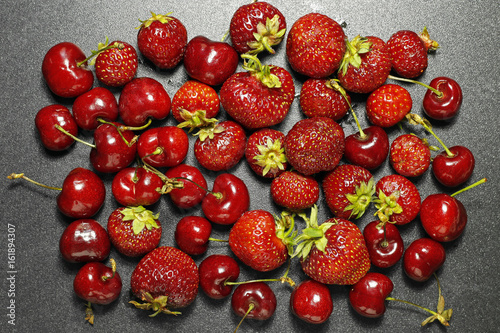 fresh summer fruits background- strawberries and cherries on dark background