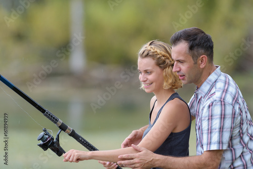 boyfriend teaches his girlfriend to use a fishing rod