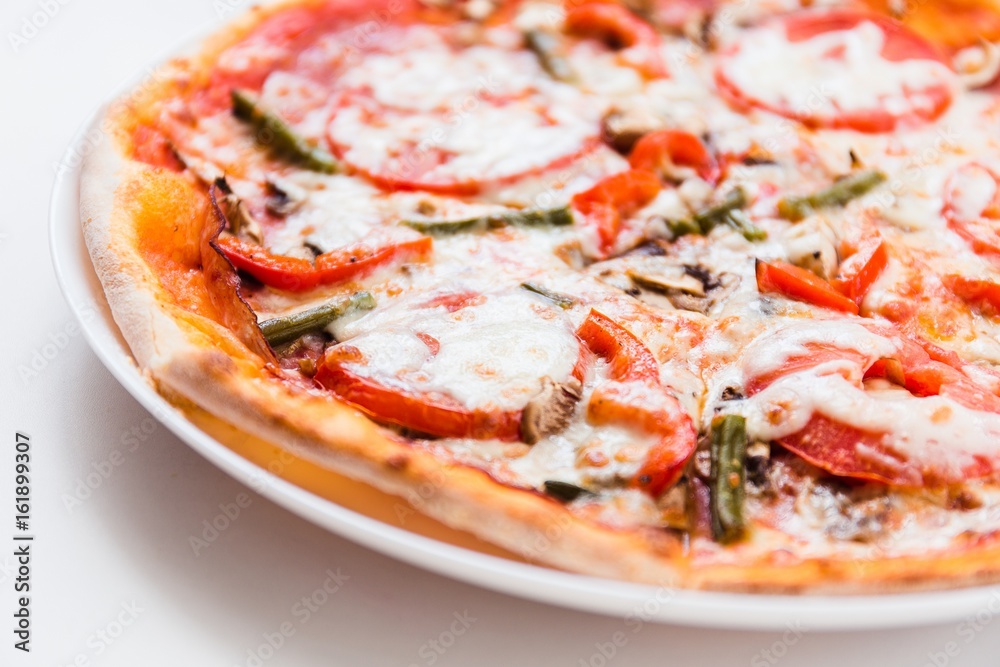 Pizza with tomato, mushrooms, bell peppers on a white plate on a light background Pizza with tomato, mushrooms, bell peppers on a white plate on a light background