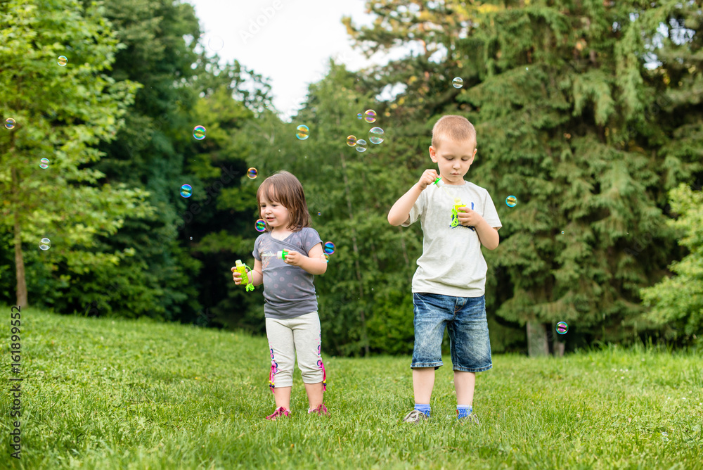 Fototapeta premium Kids on a meadow are blowing bubbles