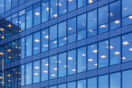 office building windows with inner artificial lamplight in blue color tone