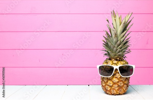 Photo Hipster pineapple with sunglasses against a pink wooden background