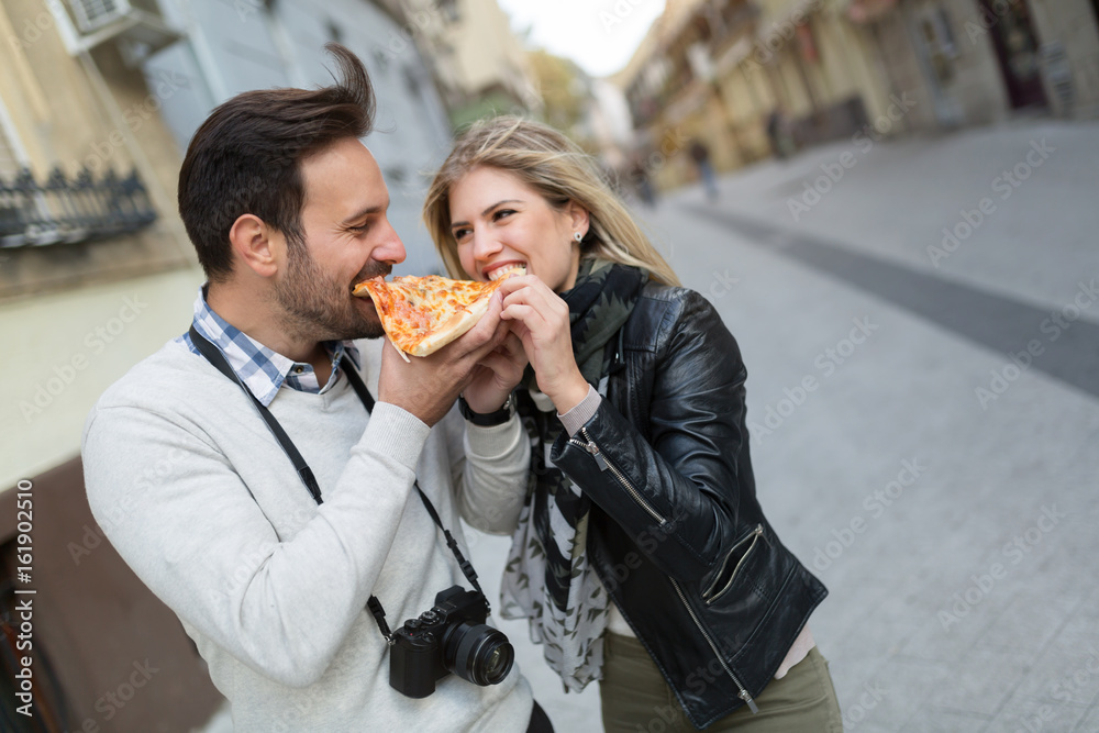 Young attractive couple sharing slice of pizza