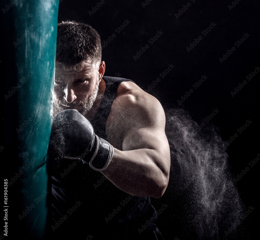 Studio shot of male boxer punching a boxing bag. Photos | Adobe Stock