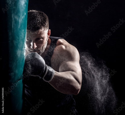 Studio shot of male boxer punching a boxing bag.	