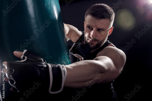 Studio shot of male boxer punching a boxing bag.  © Zoran Zeremski