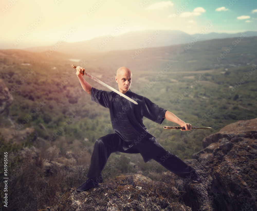 Wushu master with sword, meditation on mountain