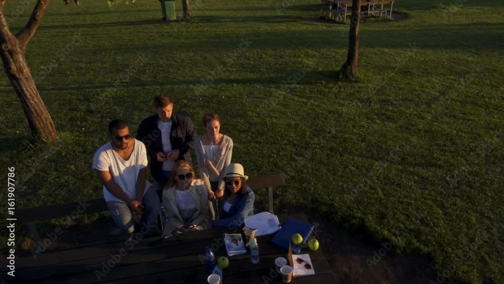 Multi-ethnic group of friends drinking coffee and chatting in a park