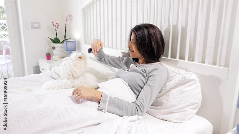 Woman in bed being licked in face from puppy dog Woman in bed being licked in face from puppy dog