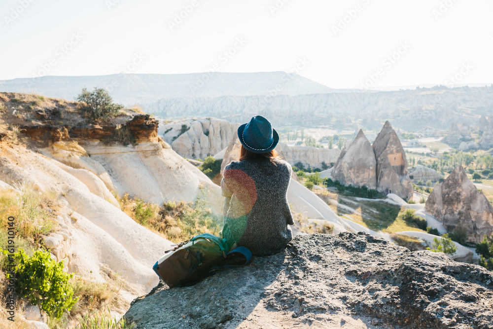 Εκτύπωση καμβά A traveler in a hat with a backpack stands on a mountain and looks at a beautiful view in Cappadocia in Turkey