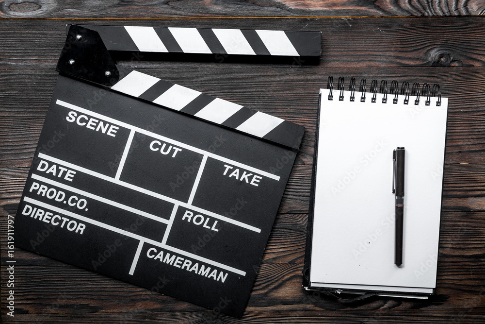 Work table of producer. Movie clapperboard and notebook on wooden table background top view