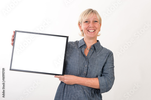 beautiful european mid aged woman in business dress holding a blank white board - studio shot in front of a white background