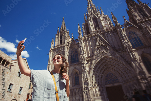 Photography Young and happy tourist woman making selfie photo in front of cathedral in Barce