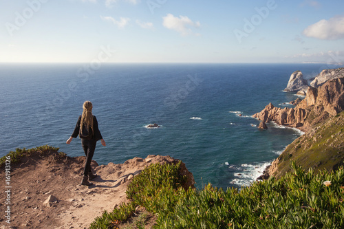 Woman staying on ocean cliff, tourist at westernmost point of Europe, Cabo da Roca, Portugal