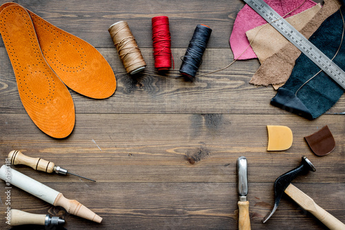 Working place of shoemaker. Skin and tools on brown wooden desk background top view copypace