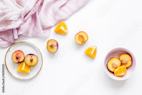 woman summer breackfast with orange and peach fruits and fabric on white background flat lay photo
